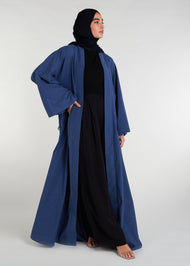 Waist pleats create a flowy silhouette, accompanied by wide sleeves and a stylish kimono style. The denim blue color adds to its overall appeal, while pockets provide functionality.