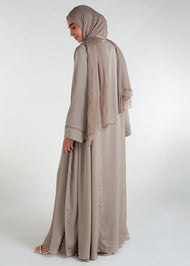 This open abaya in beige is the perfect addition to any wardrobe. Its loose fit and neutral colour make it versatile and suitable for a variety of outfits. The delicate lace trim adds a feminine touch to complete the look.