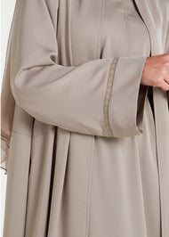 This open abaya in beige is the perfect addition to any wardrobe. Its loose fit and neutral colour make it versatile and suitable for a variety of outfits. The delicate lace trim adds a feminine touch to complete the look.