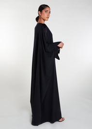 This loose fit classic black kaftan features a luxurious satin strip across the neck line and sleeves, adding an elegant touch to its modest cut silhouette. Ideal for various occasions.