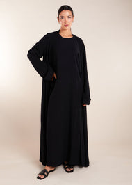 This elegant Two Piece Open Abaya set includes a Full Sleeve matching inner dress. Perfect for everyday wear, it can also be dressed up with accessories for an evening look. The open abaya can be worn as a maxi on its own or paired with the inner dress for a stylish ensemble. In black.