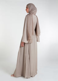 This waist pleat abaya in beige boasts a flattering fit with light pleating on the waist and bodice. Perfect for summer, the flared bell sleeves add a breezy touch, while the discreet button opening on the front of the bodice adds a thoughtful detail.