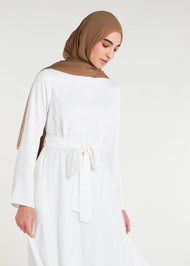 This fully lined white abaya boasts subtle pleats strategically placed at the waist to gently accentuate your figure. An optional belt is included for those who prefer a cinched waist. 